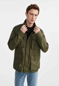 Jasnozielona kurtka użytkowa wykonana z lekkiego materia łu, z zamkiem błyskawicznym, dwoma kieszeniami na piersi i zapięciem na guziki z przodu.