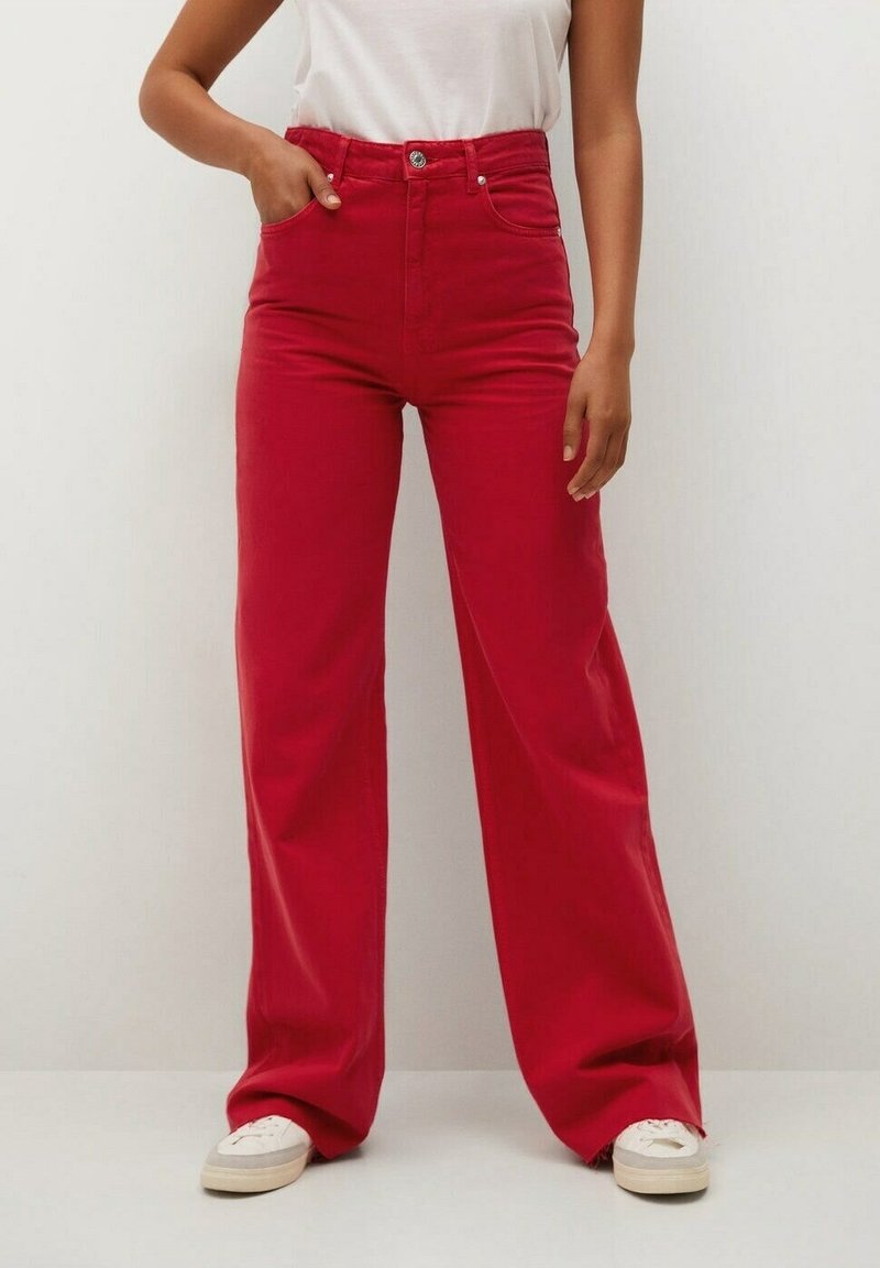 Pantalons larges taille haute rouges en coton. Dotés d'une fermeture à bouton à l'avant et de poches latérales. Stylés avec un haut blanc et des baskets.