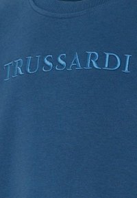 Felpa blu con logo "TRUSSARDI" in rilievo dello stesso blu, colletto a costine e texture del tessuto liscia.