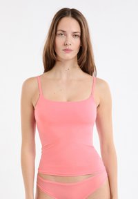Różowy dopasowany top na ramiączkach z cienkimi paskami i kwadratowym dekoltem. Wykonany z gładkiego, elastycznego materiału, sięga tuż powyżej talii.