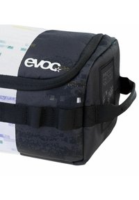 Bolsa compacta en blanco y negro con el logo "evoc" en relieve. Cuenta con material texturizado, asa lateral y un patrón gráfico en un lado.