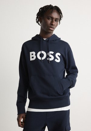 Navyblauwe hoodie van katoen, met een groot wit "BOSS" logo. Bevat een voorste kangoeroe-pocket en een capuchon met trekkoord.