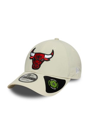 Beige cap made of fabric featuring a prominent red and black embroidered Chicago Bulls logo. Adjustable fit with logo tags on the brim.