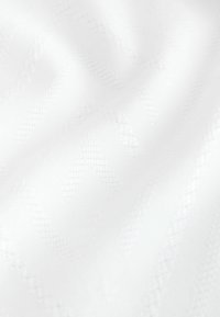 Tela blanca con un sutil patrón texturizado en forma de chevron y pliegues suaves que crean sombras delicadas.