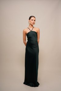 Rochie lungă, ajustată, din satin verde închis, cu un decolteu halter și bretele încrucișate, textură netedă, detalii minime.
