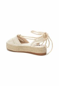 Sandalia espadrille de tela tejida en crema, con suela de yute trenzada y diseño de cordones, con tacón plano y puntera abierta.
