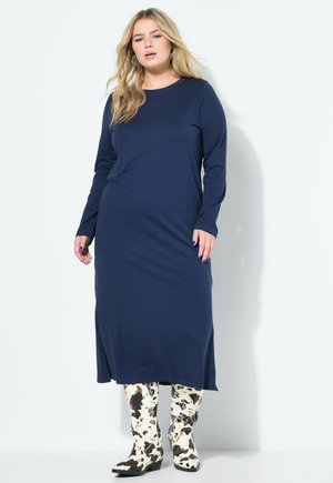 Navy long-sleeve dress made of soft fabric, featuring a straight silhouette. Paired with knee-high black-and-white cow print boots.