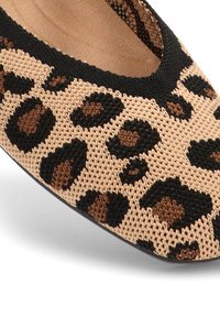 Zapato plano de estampado de leopardo que presenta una tela tejida en beige con manchas negras y marrones, puntera redondeada y suela flexible.