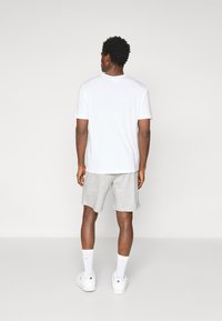 White cotton T-shirt and gray athletic shorts. The T-shirt has a crew neck, while the shorts have an elastic waistband and side pockets.