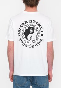 Witte katoenen t-shirt met een grote zwarte grafiek met een draaiend ontwerp en tekst die zegt "VOLCOM STONE CO. TRUE TO THIS" op de achterkant.