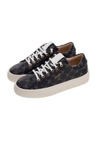 Zapatillas negras con un patrón, cordones blancos y ojales dorados. Presentan un material texturizado y una suela blanca en contraste. Logo de la marca visible.