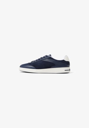 Baskets en daim bleu marine avec une semelle en caoutchouc blanche. Dotées d'un bout rond, d'un système de laçage et d'accents latéraux texturés. Style minimaliste.