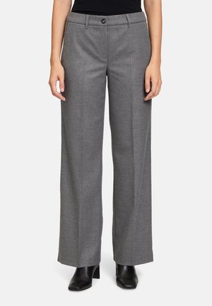 Pantalons ajustés gris avec une coupe droite, fermeture à bouton et zip à l'avant, fabriqués en tissu texturé. Portés avec des chaussures noires.