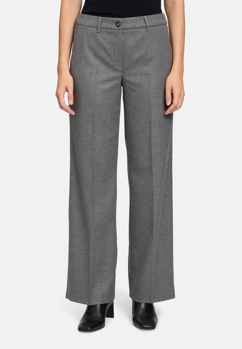 Pantalons ajustés gris avec une coupe droite, fermeture à bouton et zip à l'avant, fabriqués en tissu texturé. Portés avec des chaussures noires.