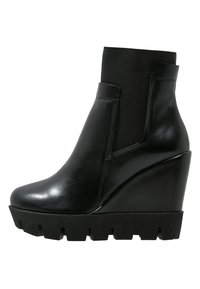 Botas de tobillo con cuña de cuero negro, panel elástico texturizado, punta redondeada y suela de goma gruesa con diseño dentado.