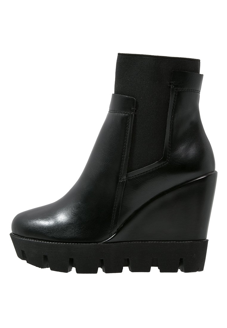 Botas de tobillo con cuña de cuero negro, panel elástico texturizado, punta redondeada y suela de goma gruesa con diseño dentado.