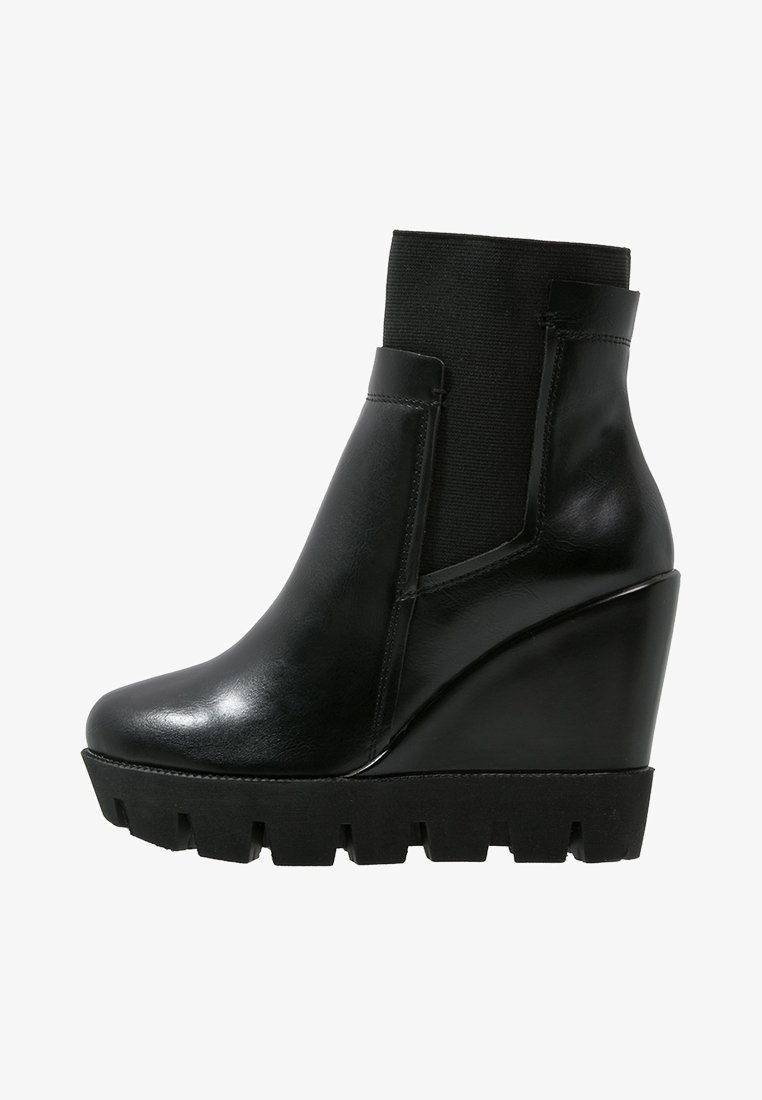 Botas de tobillo con cuña de cuero negro, panel elástico texturizado, punta redondeada y suela de goma gruesa con diseño dentado.