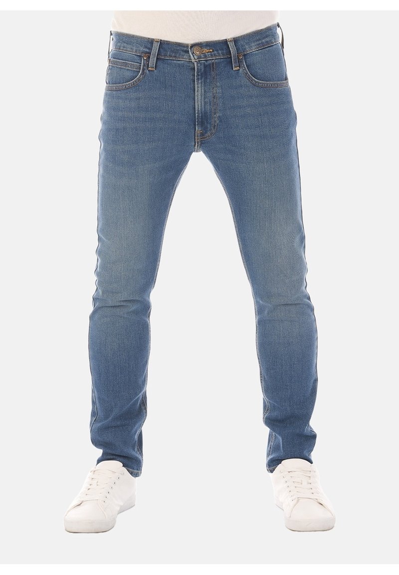 Ljust blå denimjeans med smal passform och femficksdesign. Funktionen inkluderar sydda detaljer, knäppning med knapp och bälteshällor. Bärs med vita sneakers.