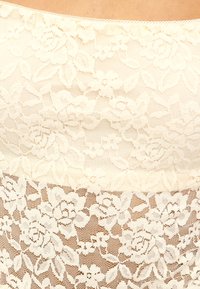 Kantstof in roomkleur met bloemmotieven; doorschijnende textuur met een gladde afwerking, met kantige randen langs de bovenkant.