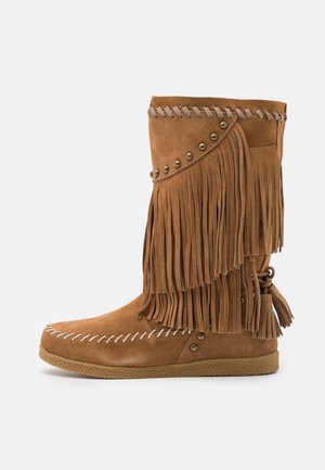 Bottines en daim marron avec de longues franges et des clous en métal, présentant un bord en dentelle décoratif et une semelle en caoutchouc texturée.