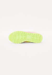 Semelle de chaussure avec de profondes rainures de traction ; jaune néon vif avec des accents roses. Le matériau semble en caoutchouc, offrant adhérence et durabilité.