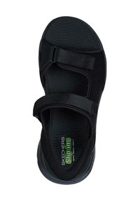 Sandalo nero con due cinturini regolabili in velcro. Soletta testurizzata e suola con motivo a scanalature. Presenta il marchio "Skechers Slip-ins".