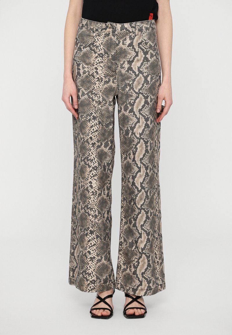 Pantaloni a gamba larga con stampa serpente in toni beige e grigi, dotati di una finitura testurizzata e design a cinque tasche, abbinati a sandali neri con cinturini.