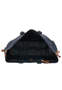 Borsa da viaggio blu navy con dettagli in pelle e un'ampia apertura. Presenta numerose tasche interne e una texture di tessuto liscia e resistente.