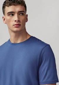 Kék pamut rövid ujjú póló, kerek nyakkivágással és sima textúrával. Minimalista dizájn, látható logók vagy minták nélkül.