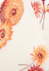 Květinová tkanina s velkými oranžovými a žlutými květy na světlém pozadí, s propracovanými detaily a jemnou, hladkou texturou.