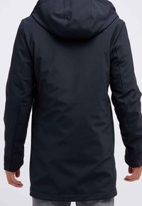 Veste noire imperméable à capuche avec manches longues portée par une personne de dos, couvrant le haut des cuisses.
