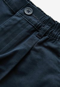 Pantalon bleu foncé avec une taille élastique, une fermeture boutonnée, des passants pour ceinture et des coutures visibles sur les poches avant.