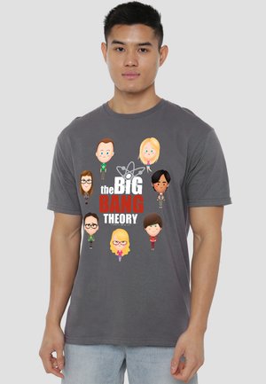 Man wearing gray t-shirt with cartoon characters from The Big Bang Theory and the show’s title printed on front.