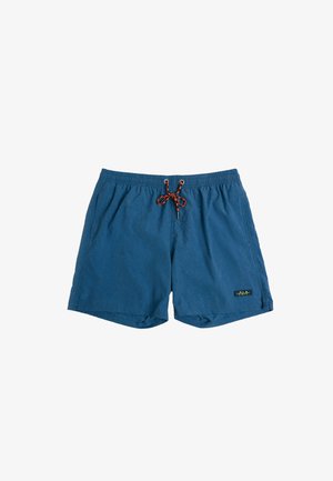 Bañadores de hombre azules con bolsillos laterales, cinturilla elástica y cordón negro-naranja, con parche de logo rectangular pequeño en la pierna izquierda.