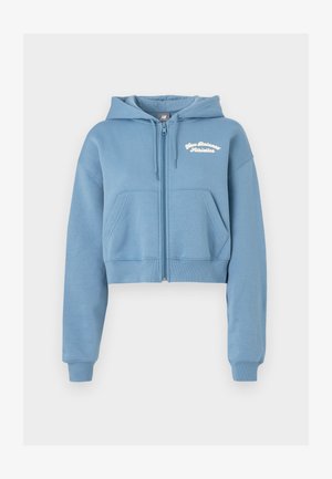 Felpa blu corta in tessuto morbido con zip frontale, due tasche anteriori e testo bianco "New Balance Athletics" sul petto.