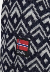 Marineblå og hvid mønstret strikstof med geometriske designs, forsynet med et mærke, der viser et norsk flag og ordet "DOVRE."
