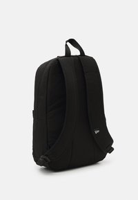 Schwarzer Rucksack aus gepolstertem Stoff, mit konturierten Trageriemen und einem Handgriff an der Oberseite. Verfügt über eine Seitentasche und ein minimalistisches Logodesign.