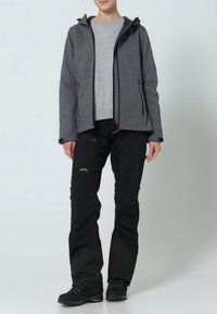 Veste grise à fermeture éclair avec capuche, dotée de deux poches avant et d'accents noirs. Pantalon noir avec détail logo et panneaux gris foncé contrastants. Bottes noires.