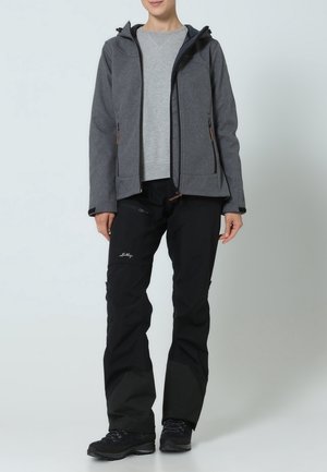 Veste grise à fermeture éclair avec capuche, dotée de deux poches avant et d'accents noirs. Pantalon noir avec détail logo et panneaux gris foncé contrastants. Bottes noires.