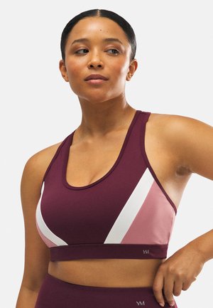 Sujeción deportiva color burdeos con acentos diagonales en blanco y rosa claro. Textura suave y diseño de espalda nadadora, con un sutil detalle del logo en el dobladillo.