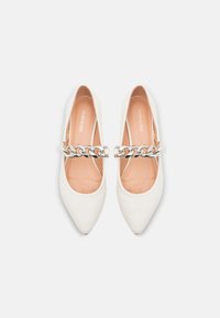Scarpe bianche a punta con una superficie liscia, dotate di un accento in catena argentata sulla parte superiore del piede. La fodera interna è di un morbido beige.