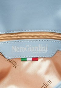Lichtblauwe leren binnenvoering met een gouden rits, het ingedrukte logo "NeroGiardini Made in Italy" en een klein Italiaans vlagaccent.