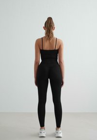 Musthave mustrida mustri tippidega, mis on paaritatud kõrge vöökohaga mustade legginsitega. Üldine disain on peen ja keha lähedal istuv. Valged tossud lõpetavad välimuse.