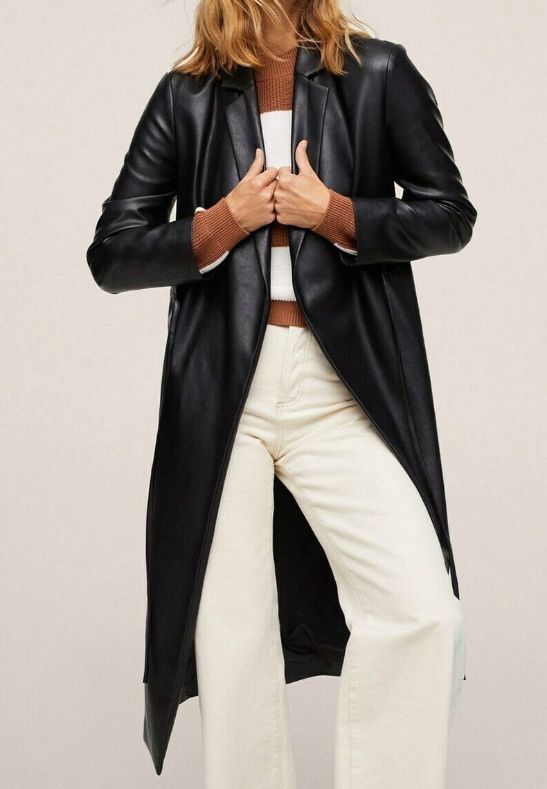 Sort læderfrakke med en skræddersyet design, der har en lang skæring og med en notch lapel. Parret med en brun og hvid stribet sweater og hvide bukser.