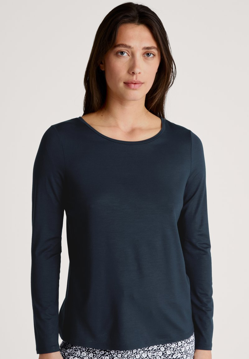 Langarm, crewneck-top in donkerblauw, met een gladde textuur. De pasvorm is ontspannen, met een rechte zoom en minimale details.