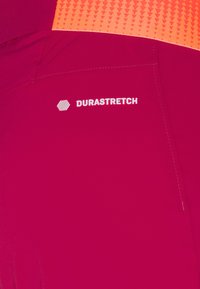 Durastretch prestanda tyg i djup rosa, med ett texturerat orange midjeband med triangulära mönster och vit logotypdetalj.