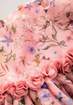 Rosa Blumenkleid aus weichem Stoff mit verschiedenen Blumen und Grünpflanzen. Verziert mit mehrlagigen rosa Stoffblumen entlang des Saums.