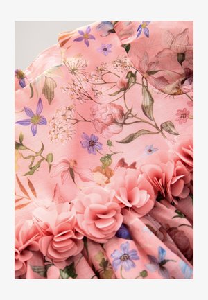 Robe florale rose en tissu doux présentant diverses fleurs et feuillages. Agrémentée de fleurs roses superposées le long de l'ourlet.