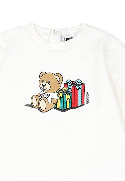 La camicia bianca a maniche lunghe presenta un orsetto di cartone animato e tre scatole regalo. L'orsetto è marrone e indossa una maglietta con la scritta "JOY"; i regali sono di colori vivaci.