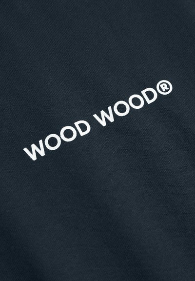 Mørkt stof med en glat tekstur, der har hvid tekst "WOOD WOOD®" trykt iøjnefaldende på midten.